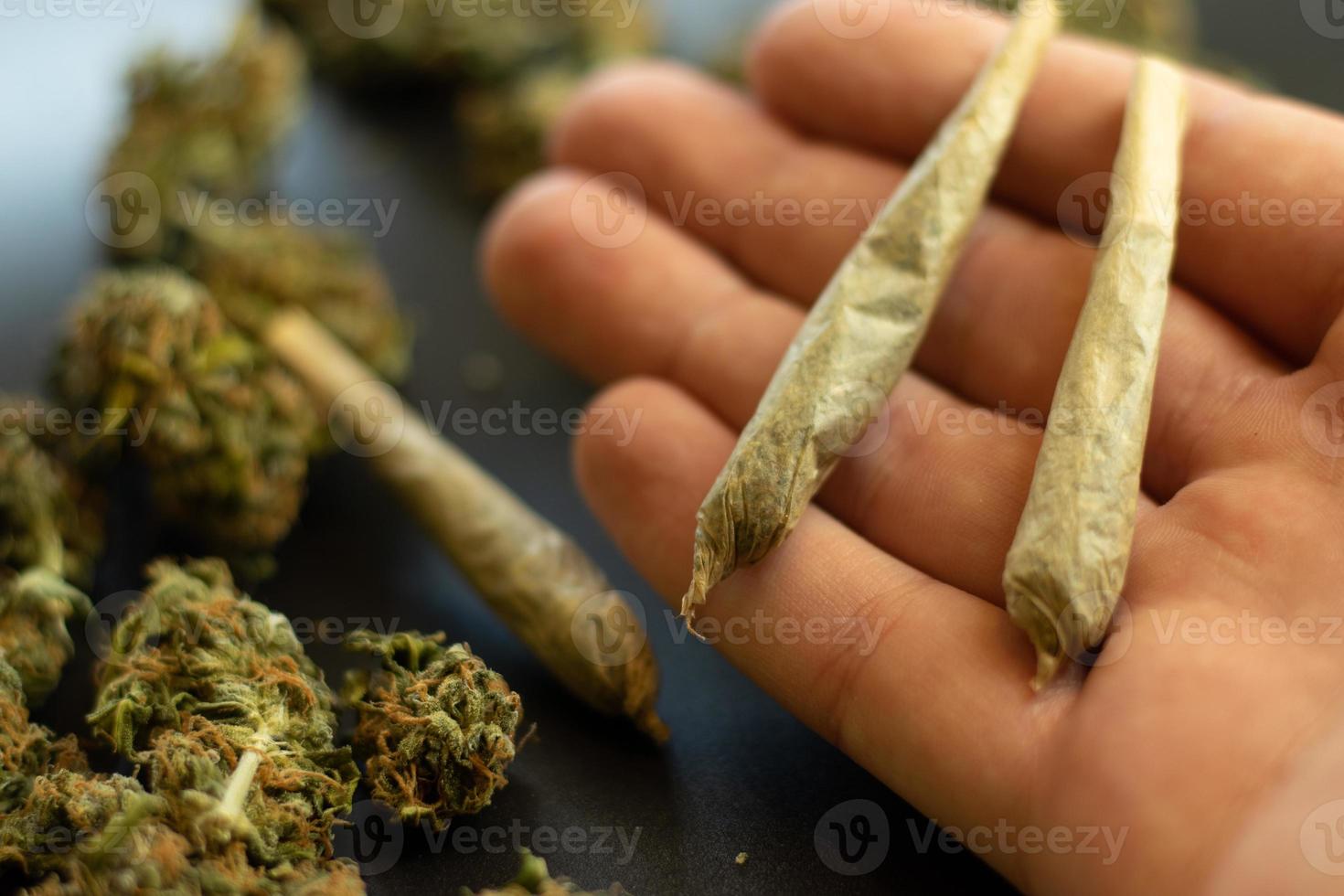 Kegel-Cannabis-Gelenke, Nahaufnahme auf der Handfläche, verschwommener Hintergrund mit Marihuana-Knospen. Freizeitkonsum oder medizinischer Drogenkonsum. das rauchen foto