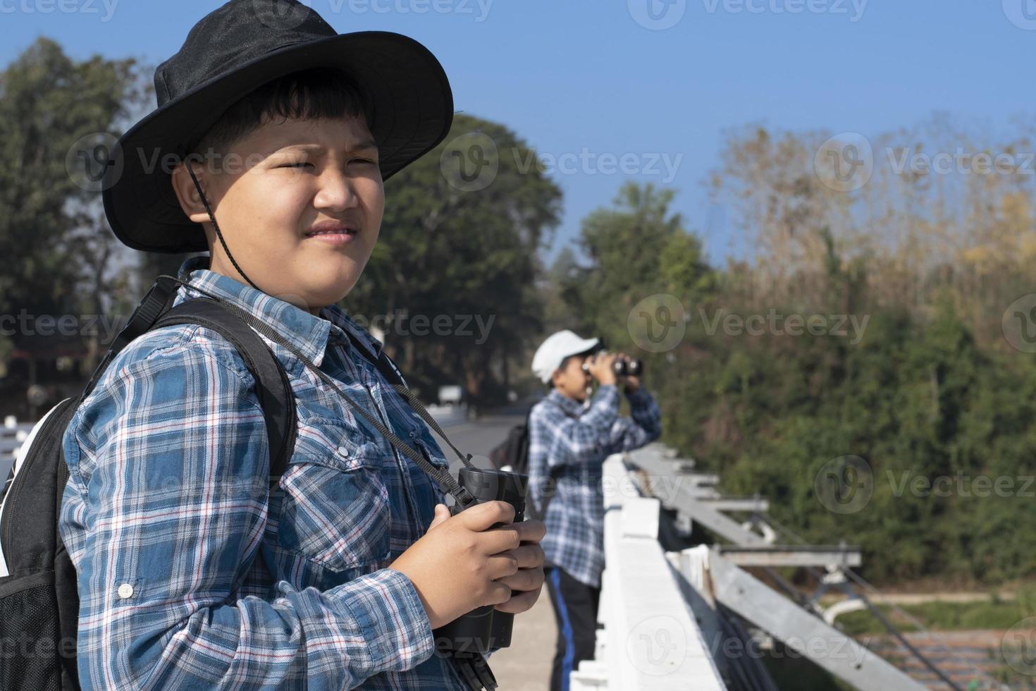 asiatische Jungen, die während des Sommercamps mit Ferngläsern Vögel auf Bäumen und Fische im Fluss im örtlichen Nationalpark beobachten, Idee zum Lernen von Kreaturen und Wildtieren und Insekten außerhalb des Klassenzimmers. foto