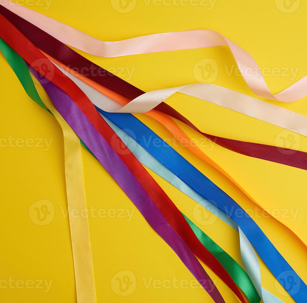 Viele mehrfarbige Seidenbänder auf gelbem Hintergrund foto