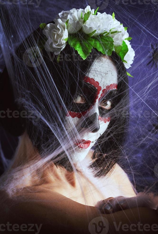 junges schönes mädchen mit traditioneller mexikanischer totenmaske. calavera catrina. Zuckerschädel-Make-up. Mädchen in einem Kranz aus Rosen gekleidet foto