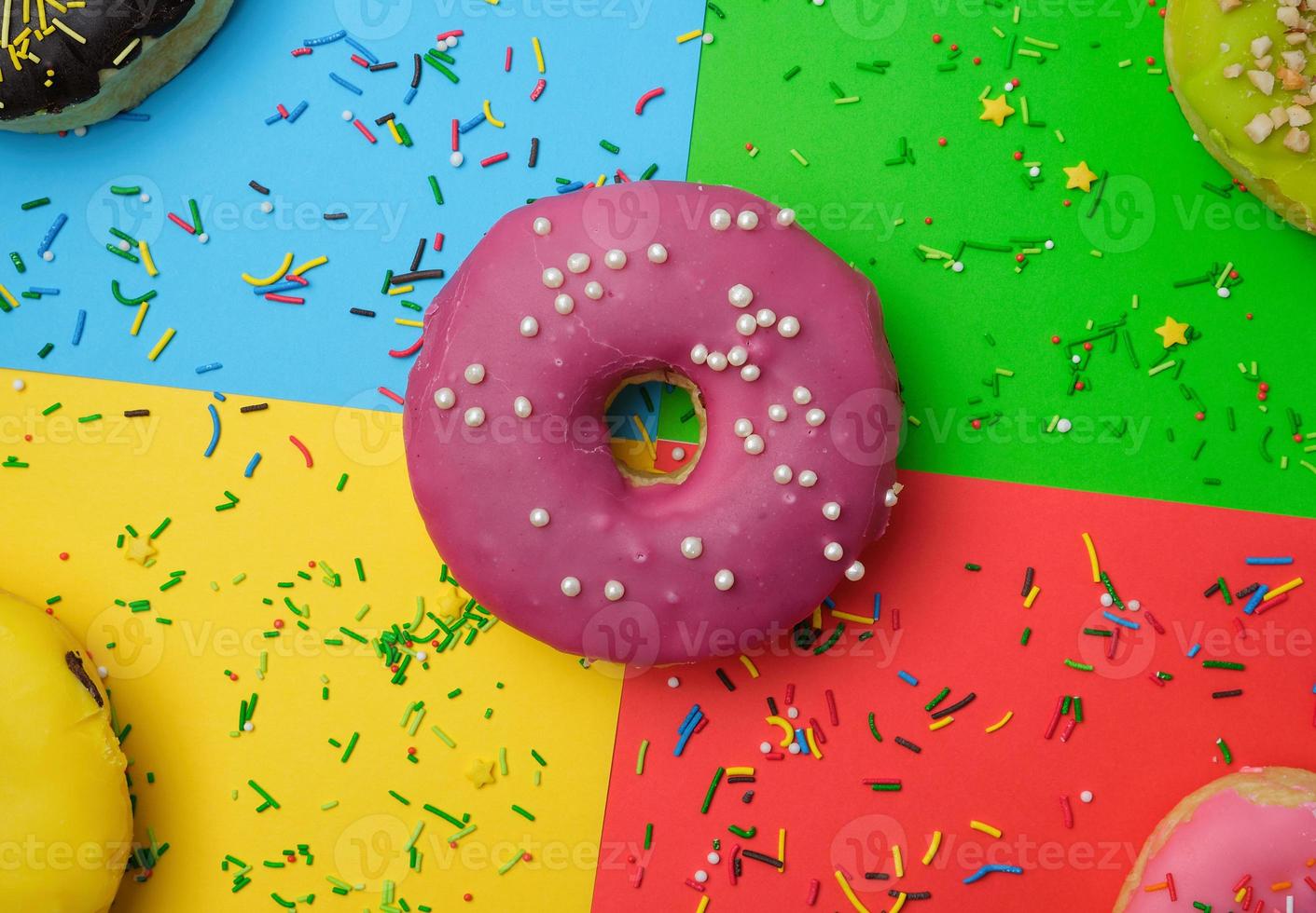 Runde verschiedene Donuts mit Streuseln auf einem hellen, mehrfarbigen Hintergrund foto