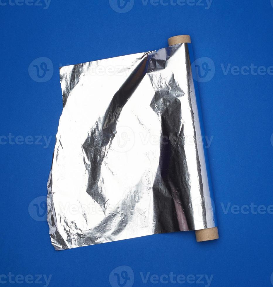 Rolle aus grauer Folie zum Backen und Verpacken von Lebensmitteln auf dunkelblauem Hintergrund foto