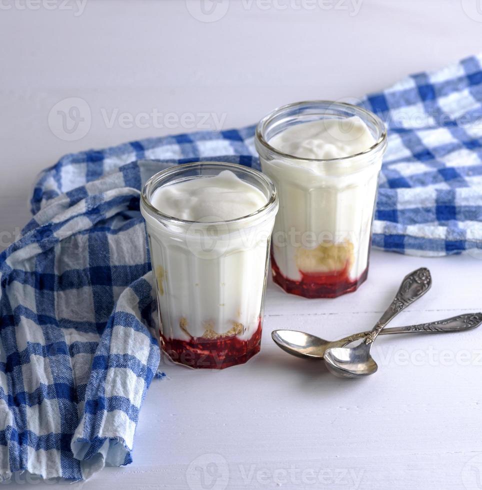 zwei Glasgläser mit hausgemachtem Joghurt und Himbeersirup foto