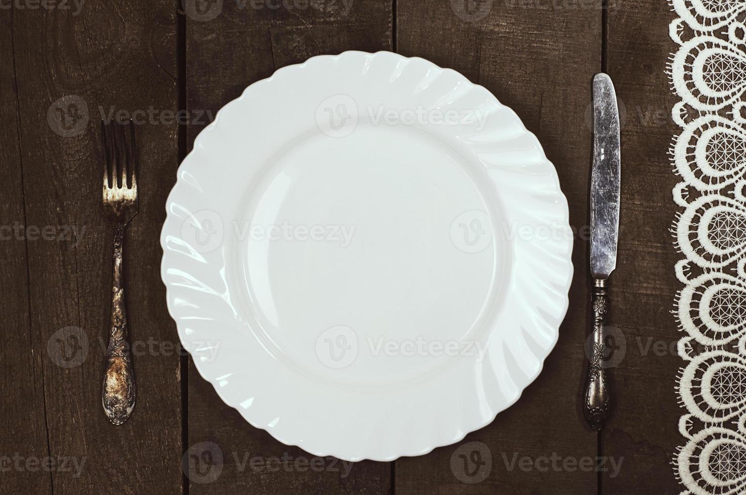 weißer Teller mit Besteck auf einer Holzoberfläche foto