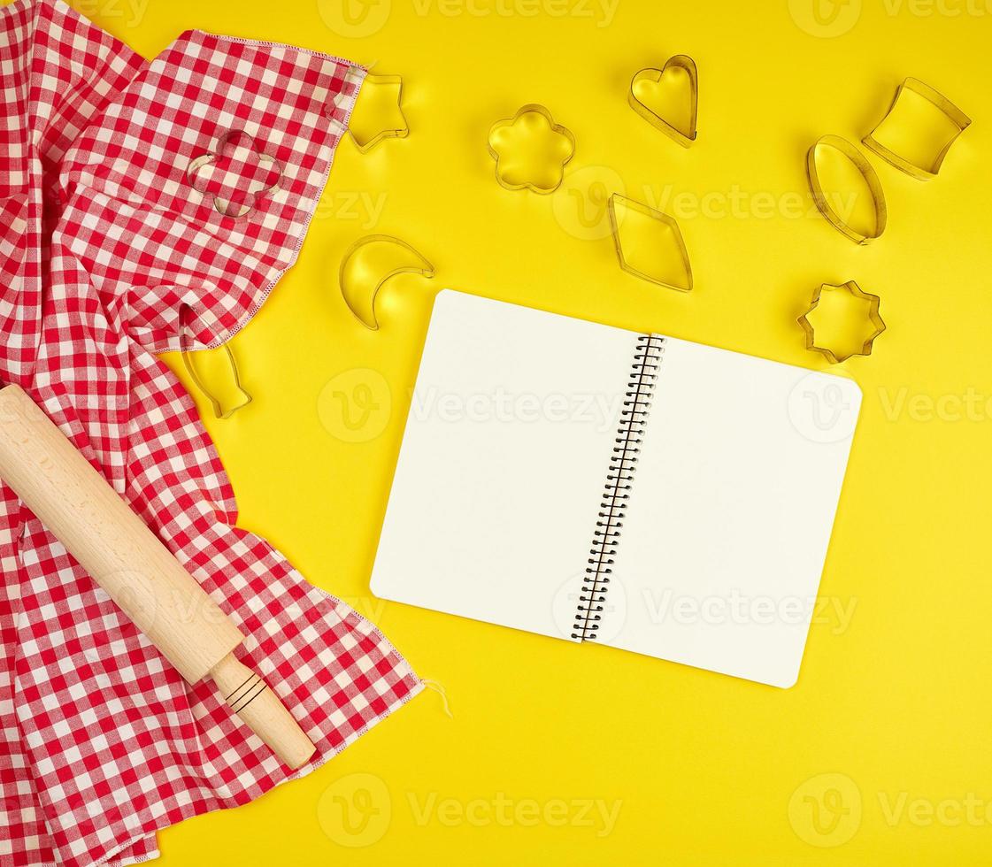 neues hölzernes Nudelholz auf einer roten Textilserviette und offenem Notizbuch foto