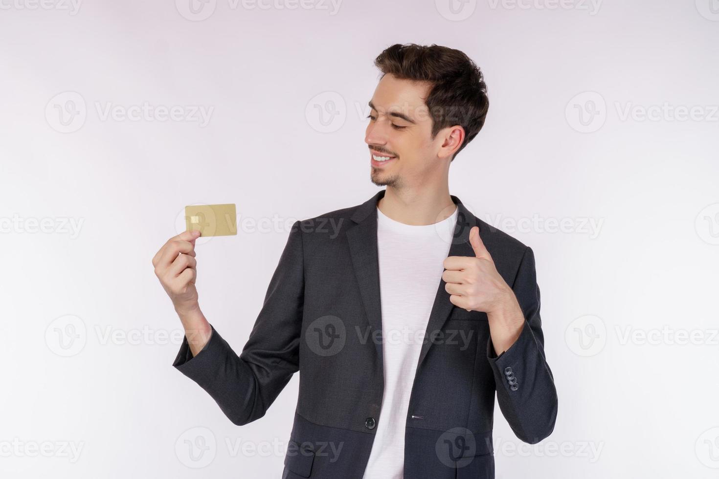 Porträt eines jungen, lächelnden, gutaussehenden Geschäftsmannes in Freizeitkleidung, der Kreditkarte und Daumen nach oben isoliert auf weißem Hintergrund zeigt foto
