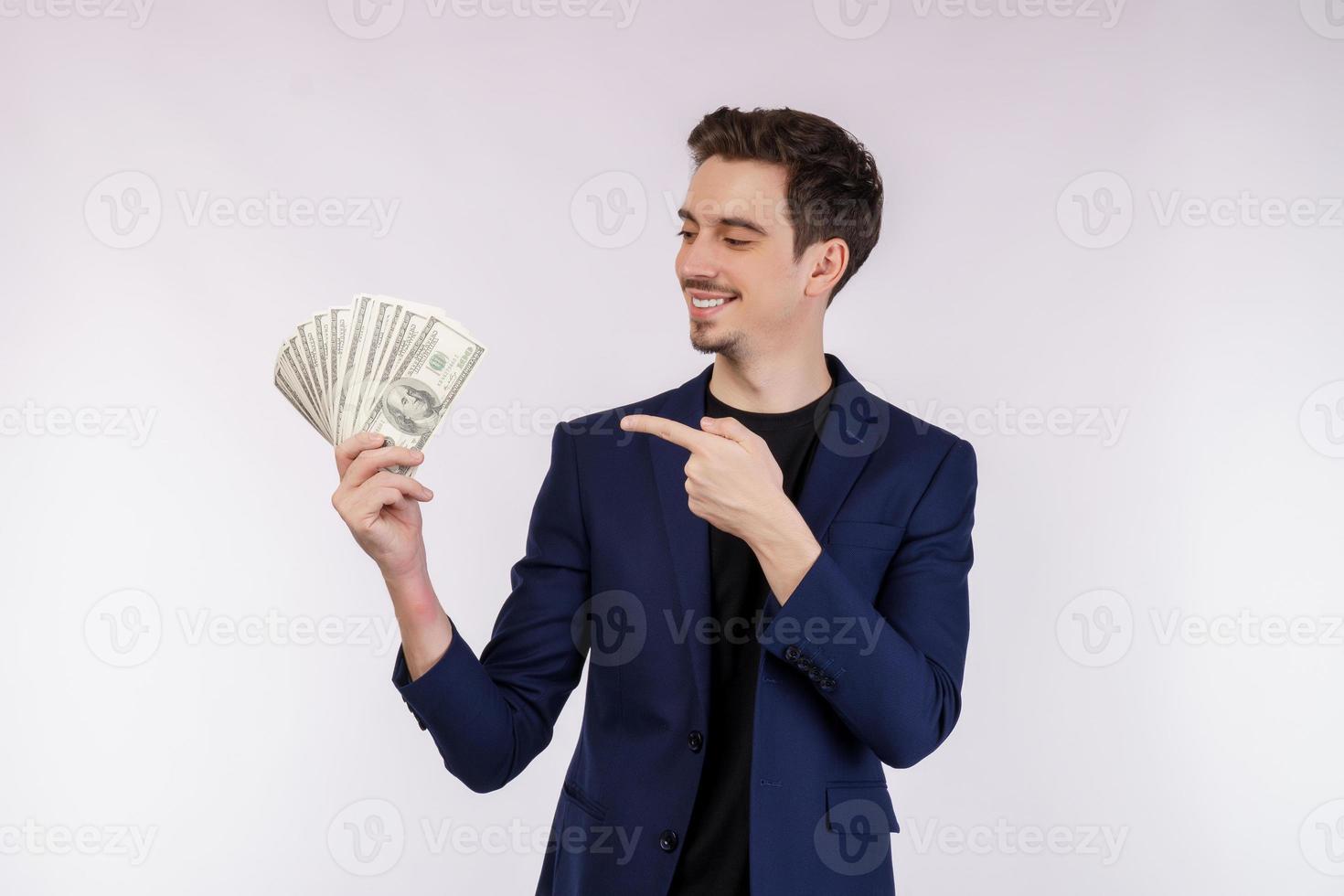 Porträt eines fröhlichen Mannes, der mit dem Finger auf einen Haufen Geldbanknoten auf weißem Hintergrund zeigt foto