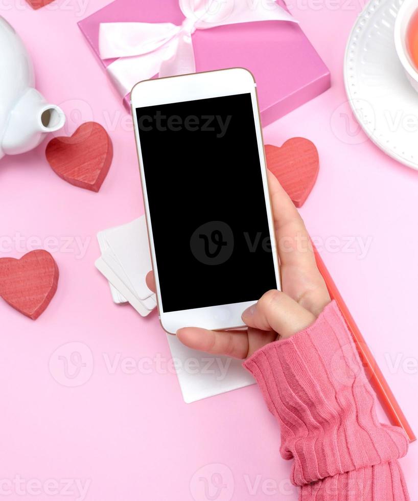 weibliche hand, die weißes smartphone mit leerem schwarzem bildschirm hält foto