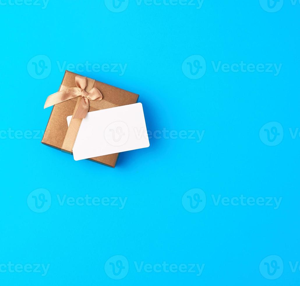 geschlossene braune geschenkbox mit schleife und leerer papiervisitenkarte foto
