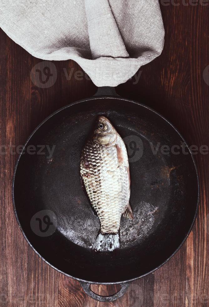 frischer Fischkarpfen in einer schwarzen Bratpfanne foto
