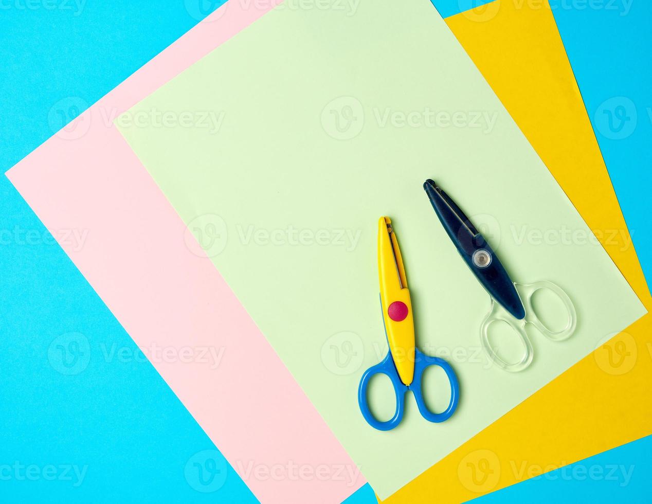 Eine Plastikschere und farbiges Papier auf blauem Hintergrund foto