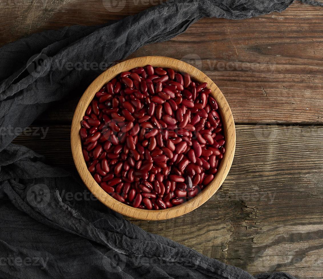 Rohe runde rote Bohnen in einem Teller auf einem Holztisch foto