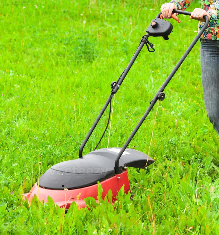 Rasenmähen, Rasenmäher auf grünem Gras foto