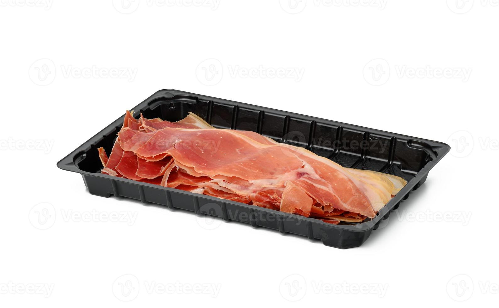 geschnittenes Prosciutto-Fleisch in dünnen Scheiben in schwarzer Kunststoffverpackung auf einem weißen Teller foto