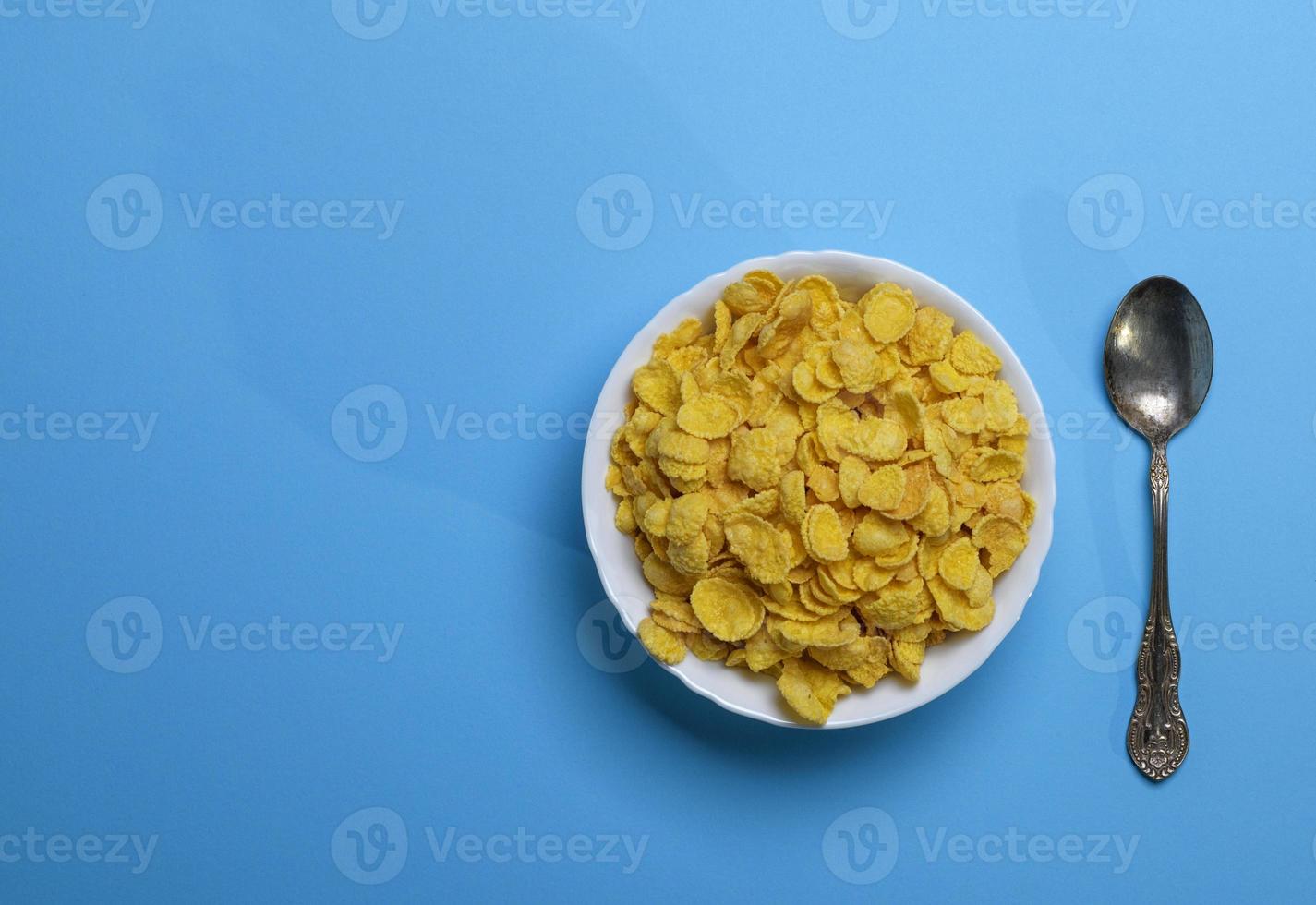 Cornflakes in einer weißen Keramikplatte und einem Eisenlöffel foto