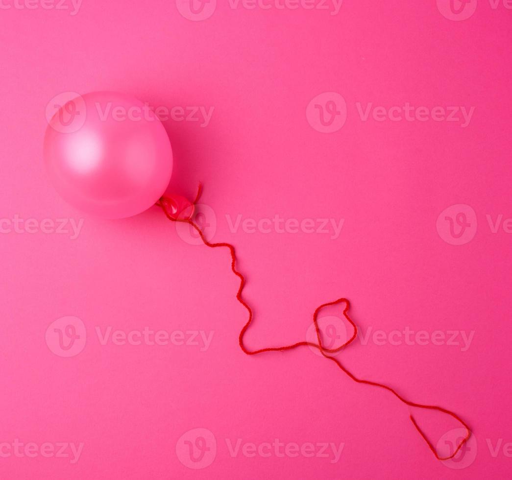 aufgeblasener rosa luftballon auf dem rosa hintergrund foto