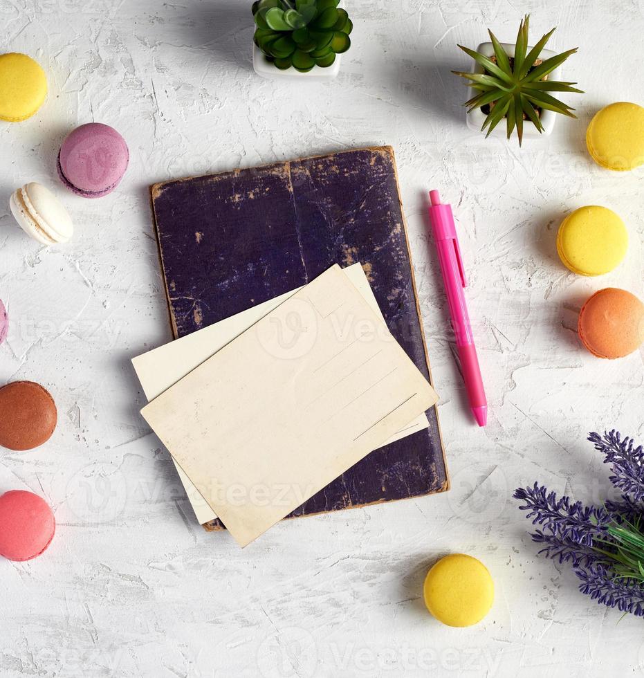 gebackene runde macarons, leere postkarten, notizbuch, rosa stift foto