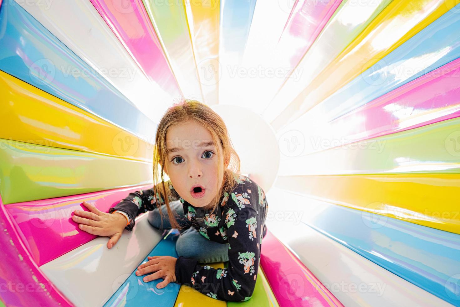 lustiges Mädchen, das auf dem Spielplatz im Indoor-Spielzentrum in farbiger Röhre spielt. foto