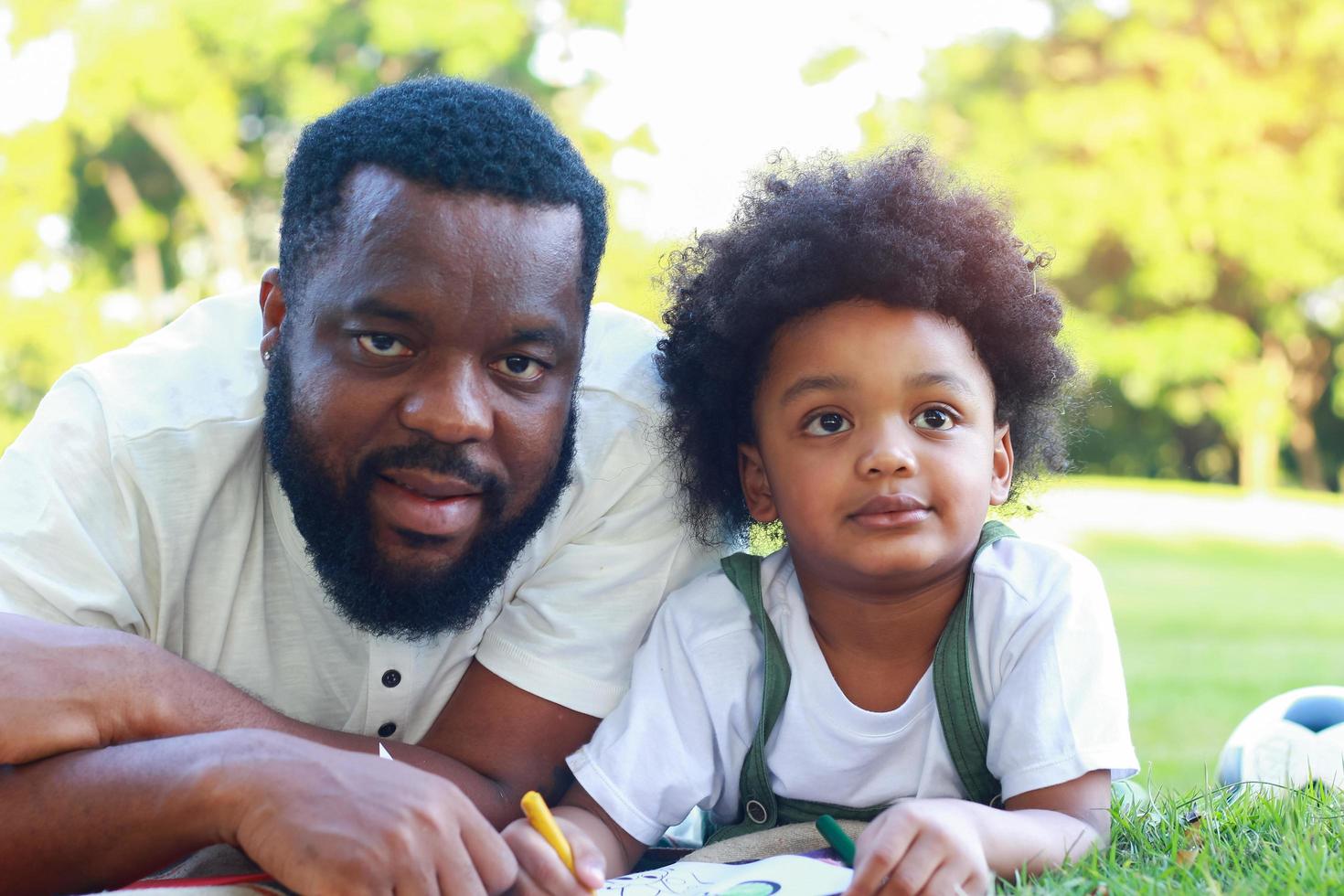 Vater und Sohn legen sich gerne im Urlaub auf den Rasen im Park. Konzept der Liebe und familiären Bindungen foto