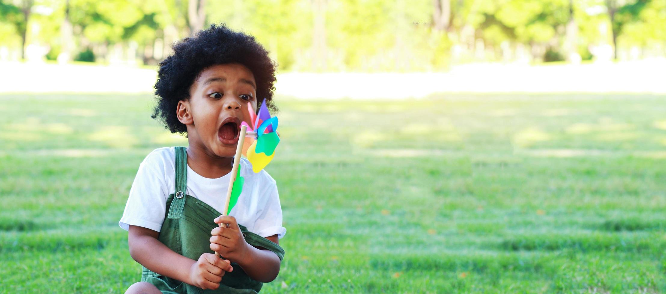 Porträt des Jungen, der freudig und glücklich im Sommer Windkraftanlage im Park spielt foto