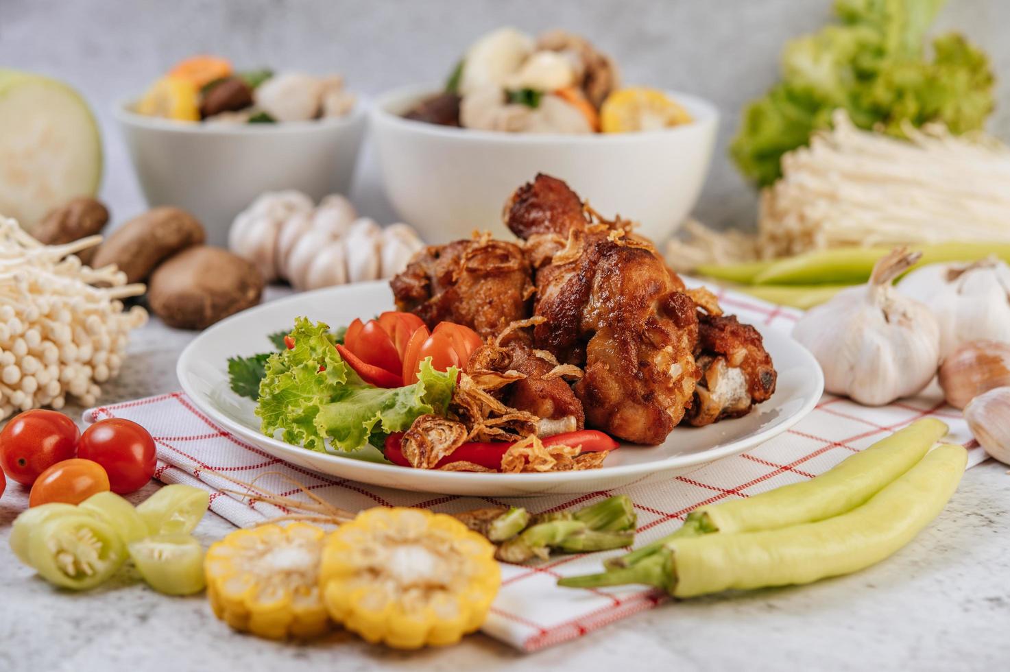 gebratene Hähnchenschenkel mit Tomaten, Chili, gebratenen Zwiebeln, Salat, Mais und Pilzen foto