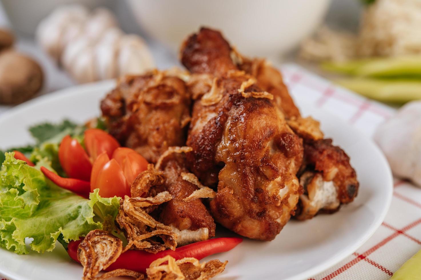 gebratene Hähnchenschenkel mit Tomaten, Chili, gebratenen Zwiebeln, Salat, Mais und Pilzen foto