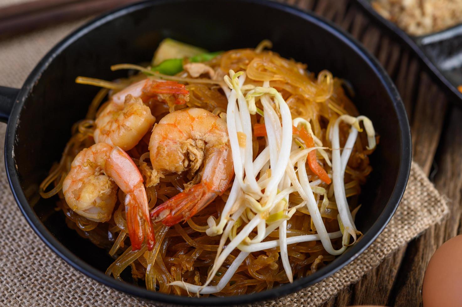 Pad Thai Shrimps in einer schwarzen Pfanne mit Eiern und Gewürzen foto