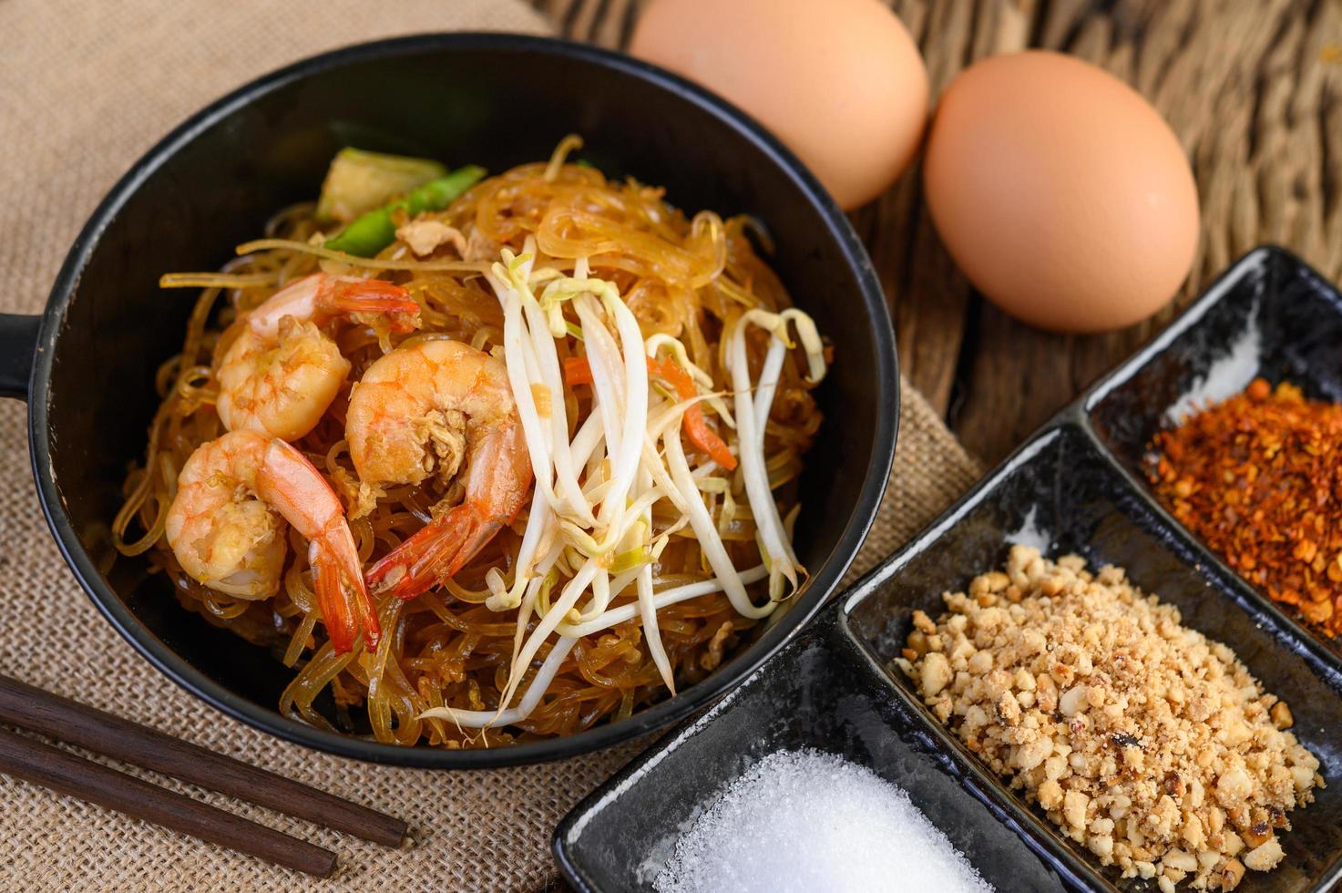 Pad Thai Shrimps in einer schwarzen Pfanne mit Eiern und Gewürzen foto