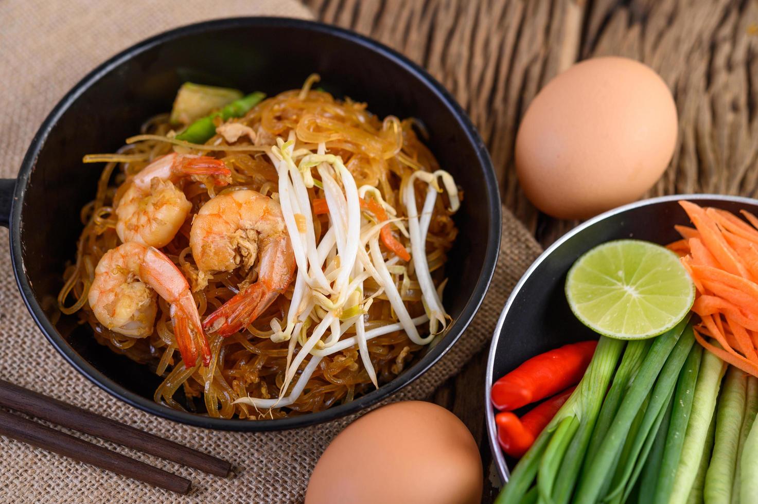 Pad Thai Shrimps in einer schwarzen Pfanne mit Eiern und Gewürzen foto