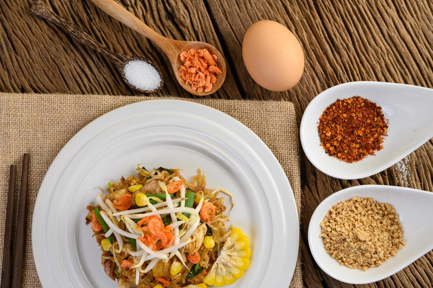 Pad Thai mit Zitrone, Eiern und Gewürzen auf einem Holztisch foto