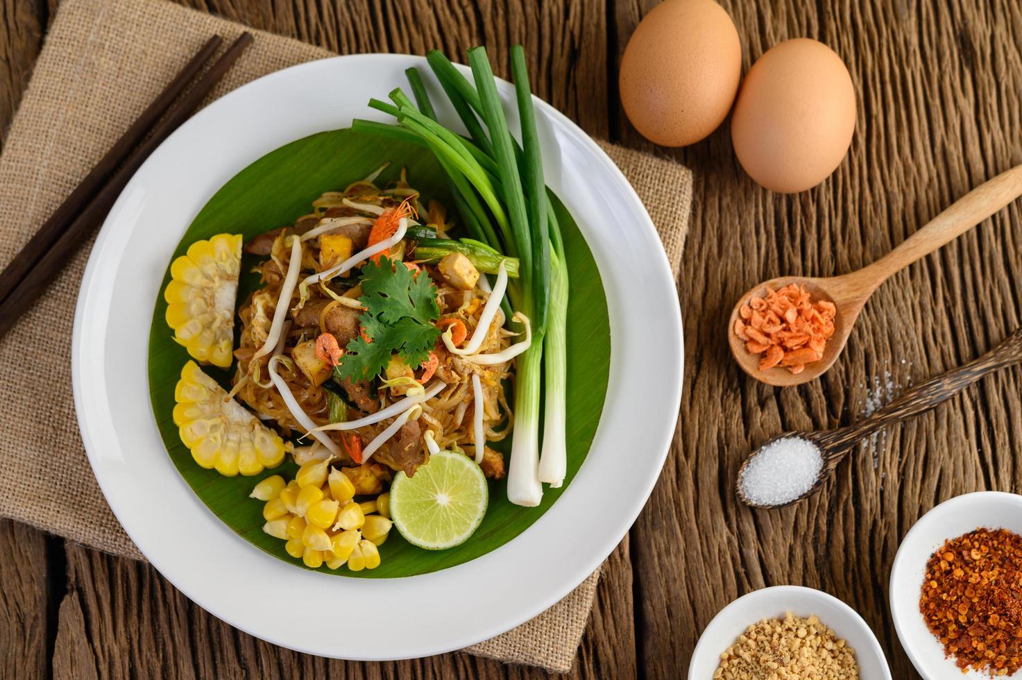 Pad Thai mit Zitrone, Eiern und Gewürzen auf einem Holztisch foto