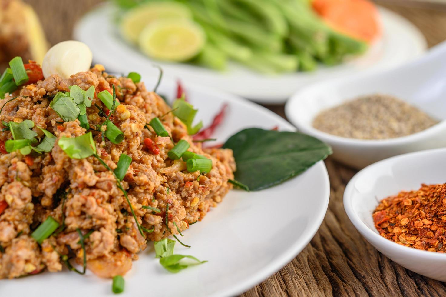 gehackter Schweinefleischsalat mit Gewürzen auf einem Holztisch foto