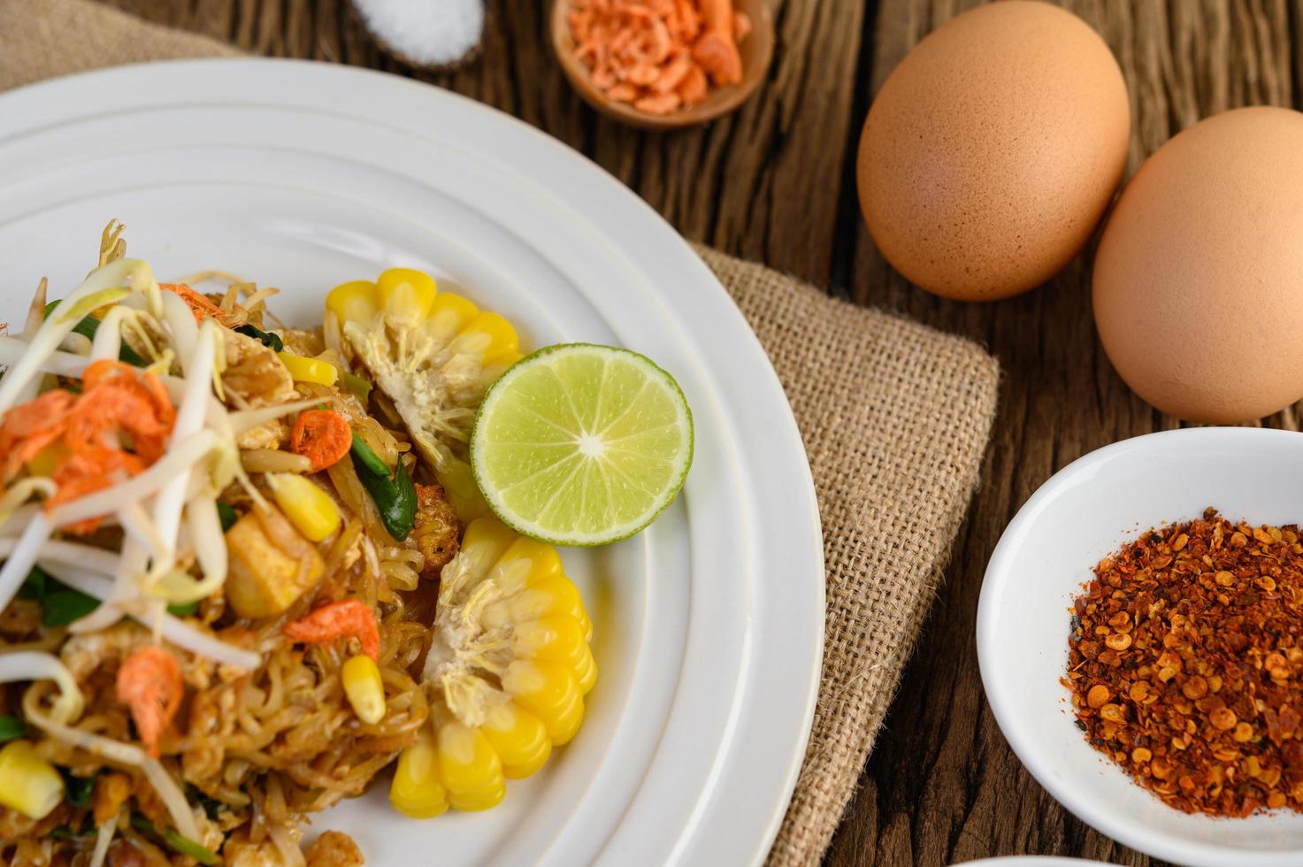 Pad Thai mit Zitrone, Eiern und Gewürzen auf einem Holztisch foto