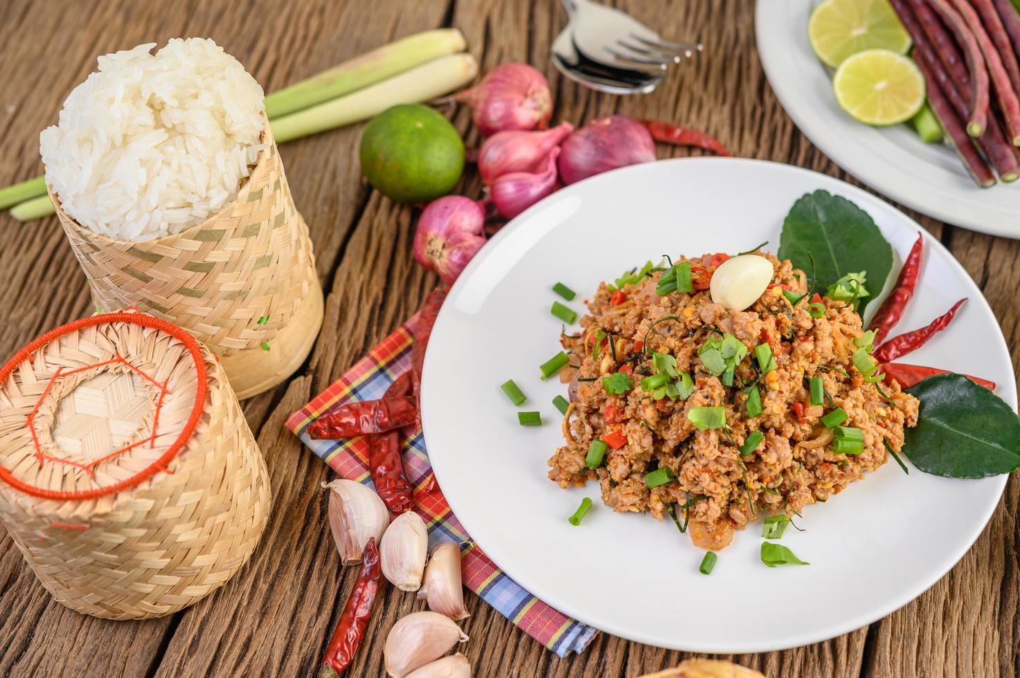 gehackter Schweinefleischsalat mit Gewürzen auf einem Holztisch foto