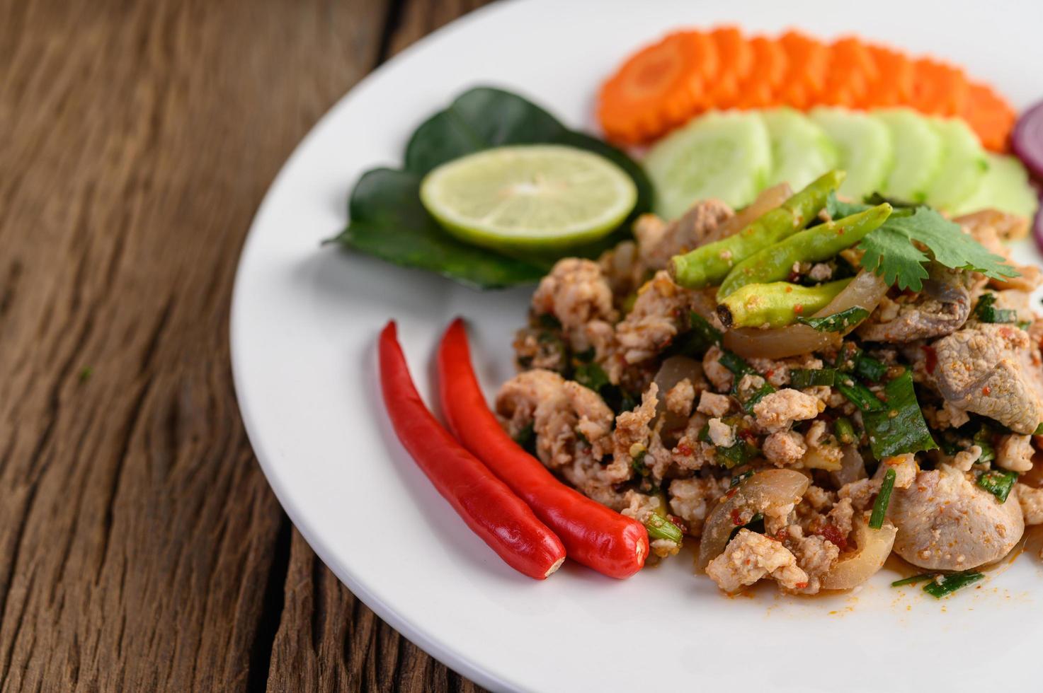 gehackter Schweinefleischsalat mit Gewürzen auf einem Holztisch foto