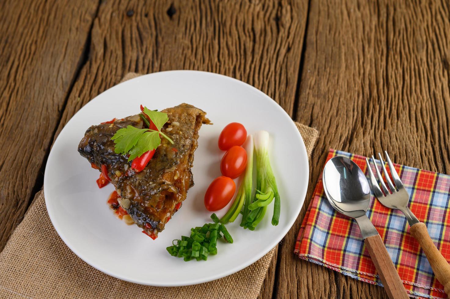 frittierter Fischkopf mit Chilis auf einem weißen Teller foto