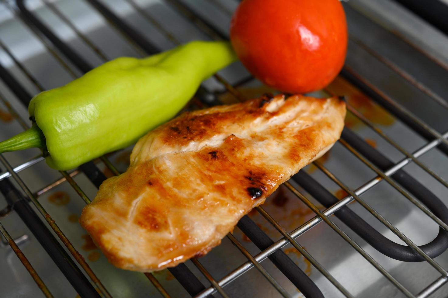 Gegrilltes Hähnchen auf einem Elektrogrill mit Paprika und Tomate foto