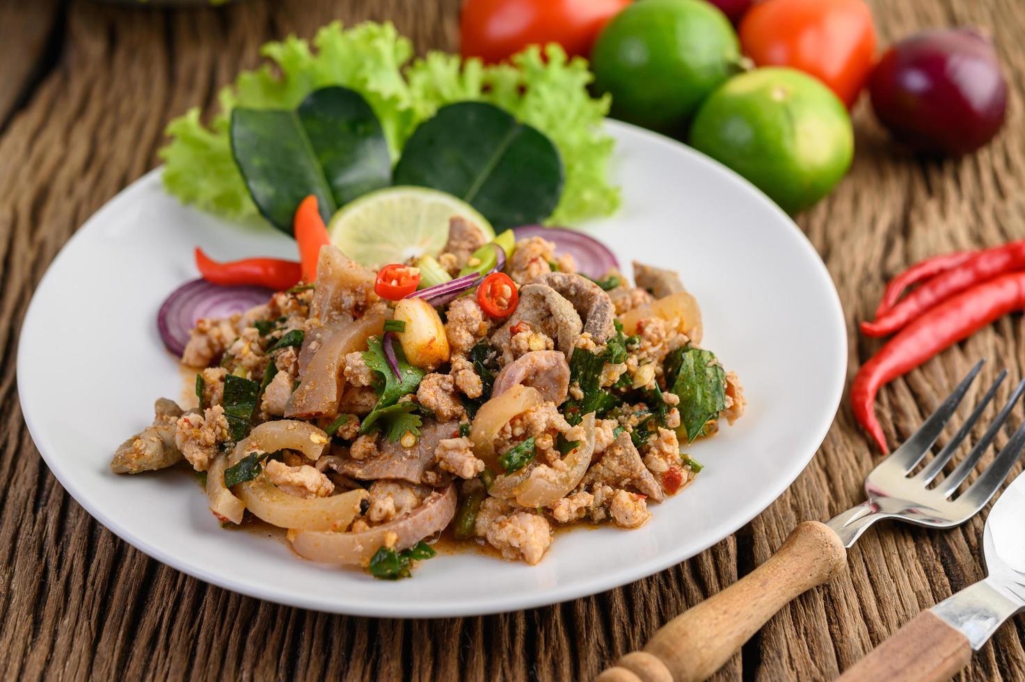 gehackter Schweinefleischsalat mit Gewürzen auf einem Holztisch foto