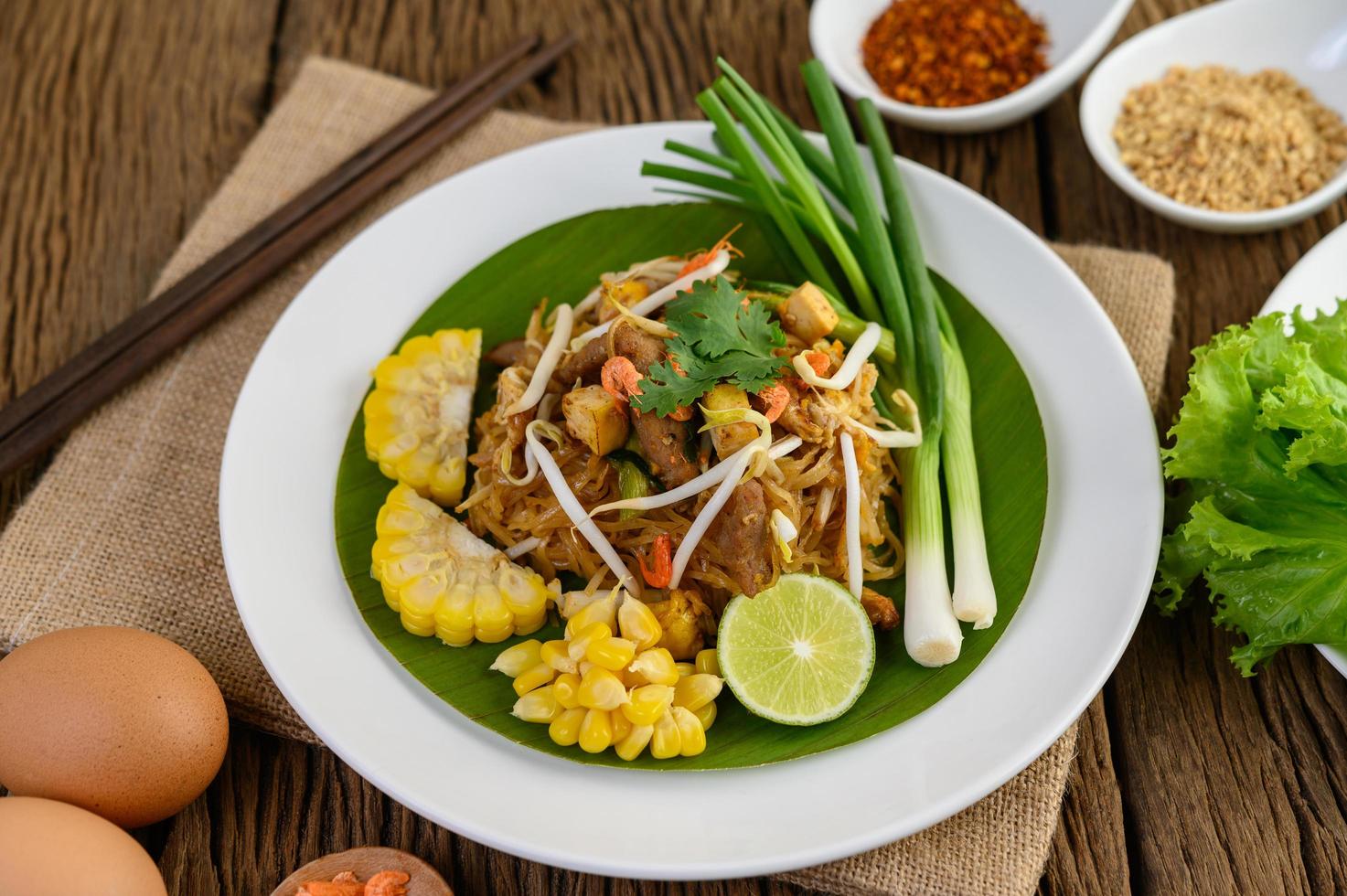 Pad Thai mit Zitrone, Eiern und Gewürzen auf einem Holztisch foto