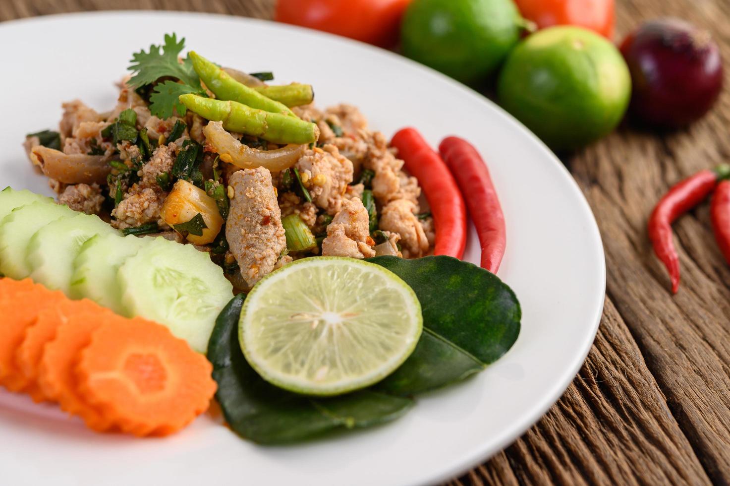 gehackter Schweinefleischsalat mit Gewürzen auf einem Holztisch foto