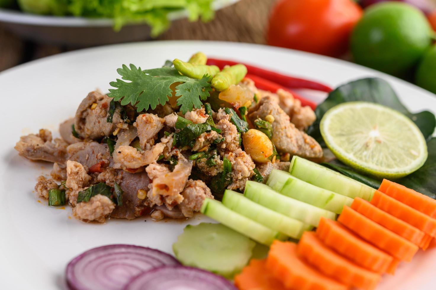 gehackter Schweinefleischsalat mit Gewürzen auf einem Holztisch foto