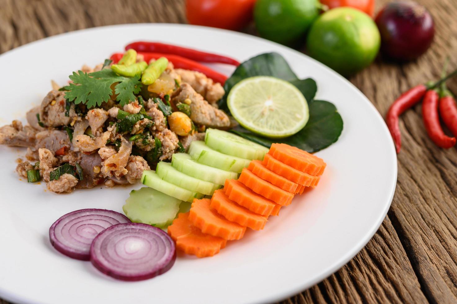 gehackter Schweinefleischsalat mit Gewürzen auf einem Holztisch foto