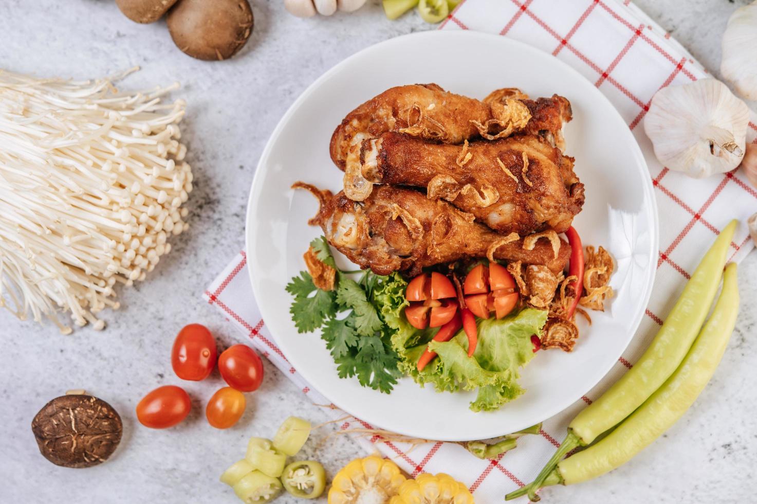 gebratene Hähnchenschenkel mit Tomaten, Chili, gebratenen Zwiebeln, Salat, Mais und Pilzen foto