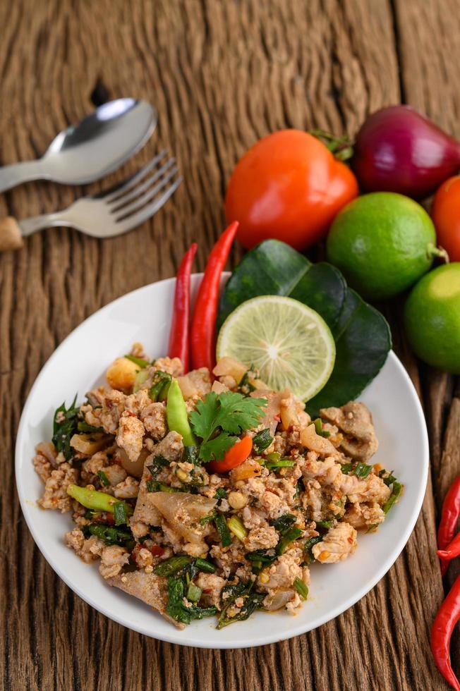 gehackter Schweinefleischsalat mit Gewürzen auf einem Holztisch foto