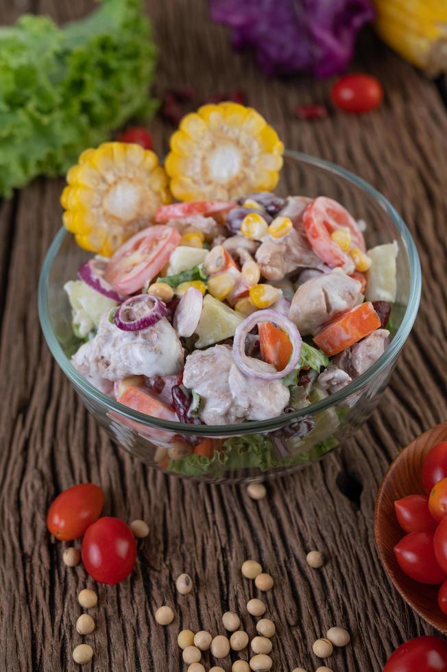 Obst- und Gemüsesalat in einer Glasschüssel auf Holztisch foto