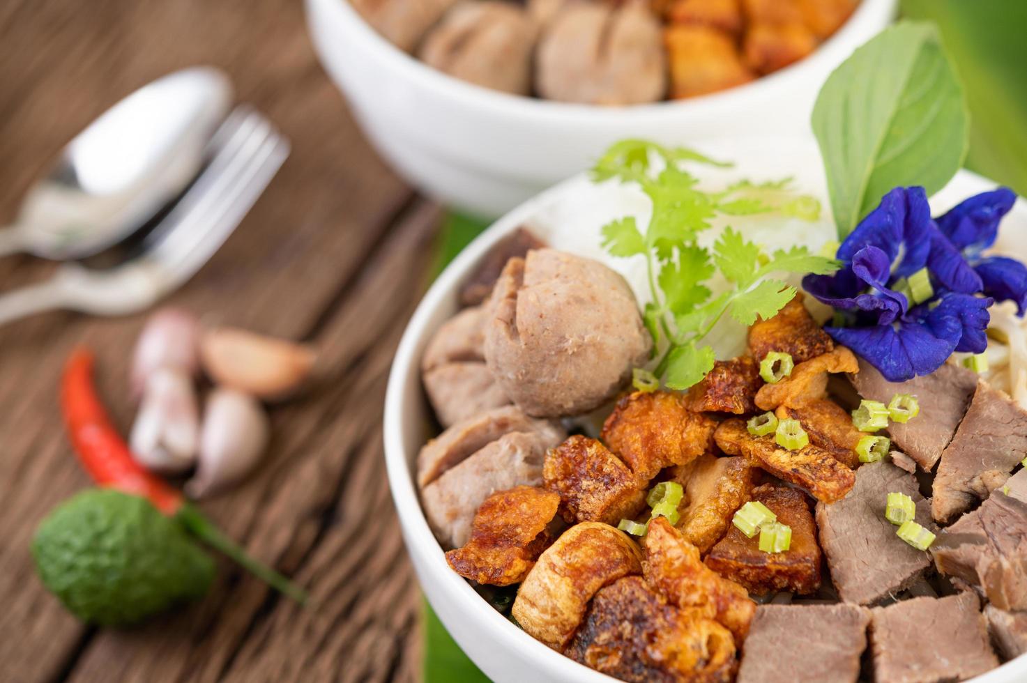 Nudeln in einer Schüssel mit knusprigem Schweinefleisch und Fleischbällchen foto