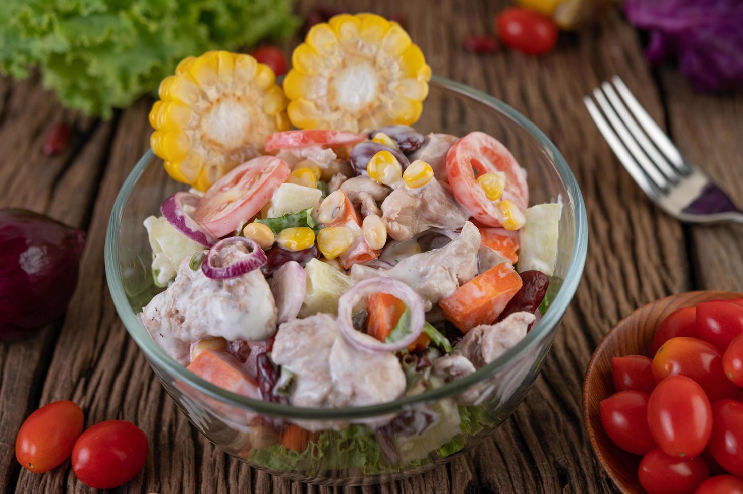 Obst- und Gemüsesalat in einer Glasschüssel auf Holztisch foto