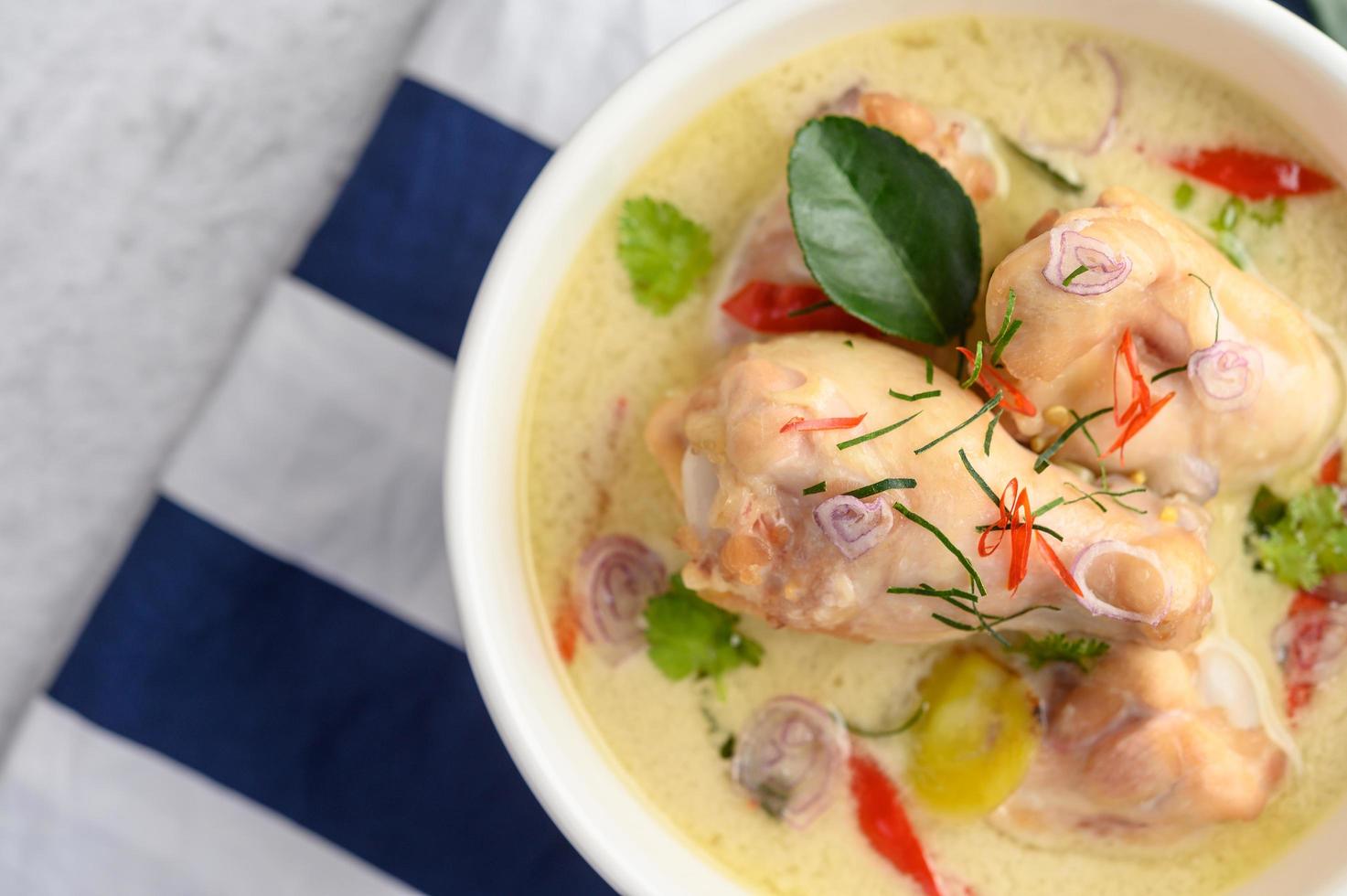 tom kha kai, thailändische Kokosnusssuppe auf einem blau gestreiften Tuch foto