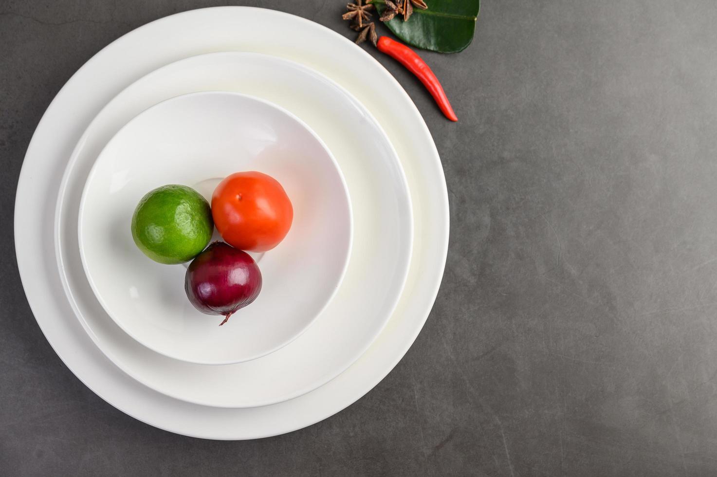 Limette, rote Zwiebel und Tomaten auf einem weißen Teller foto