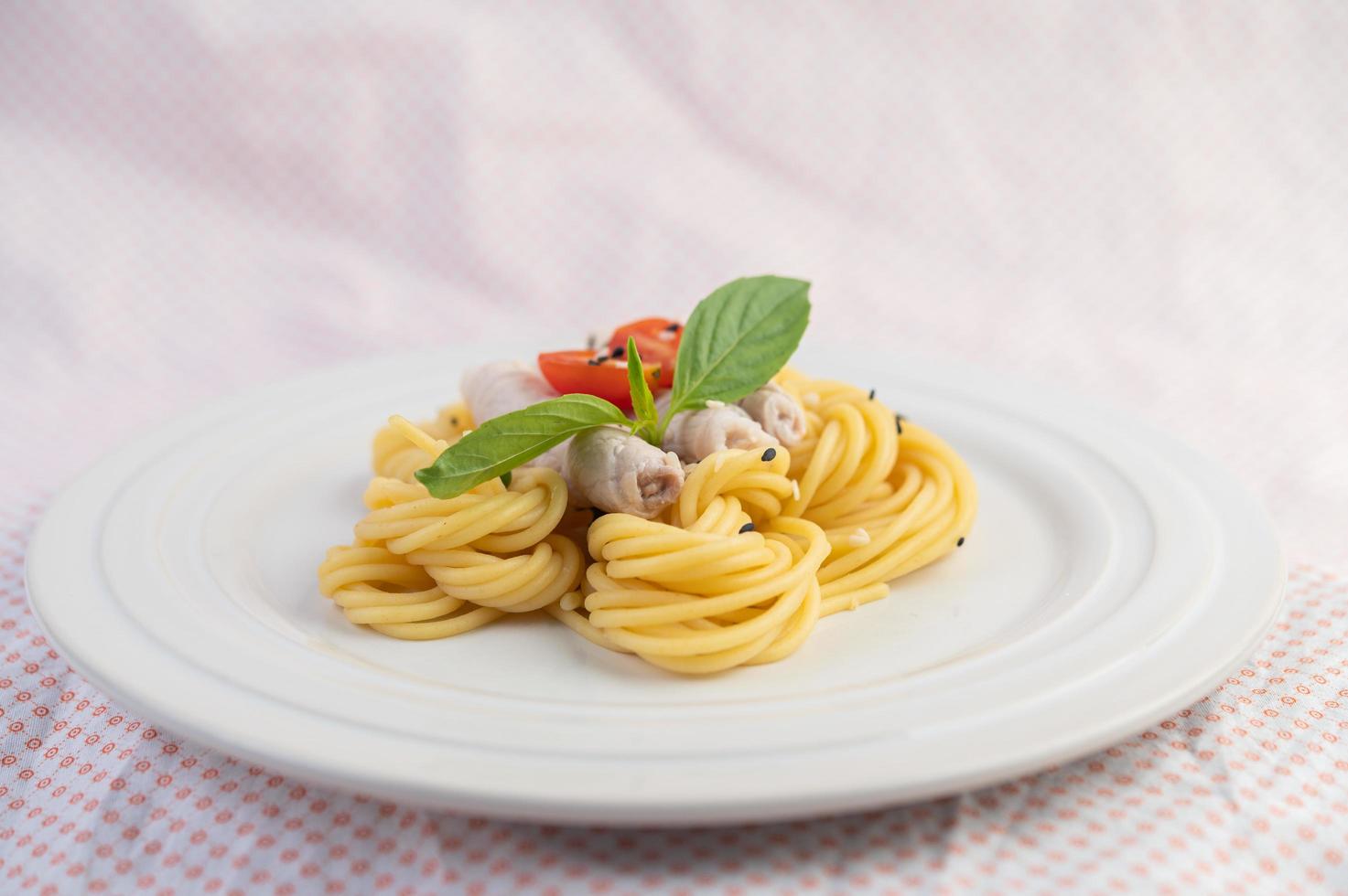 überzogene Spaghetti und Schweinefleisch auf einem weißen Teller angeordnet foto